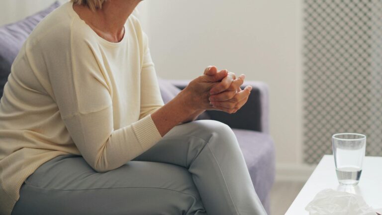 An elderly woman seated thoughtfully in an indoor counseling setting.